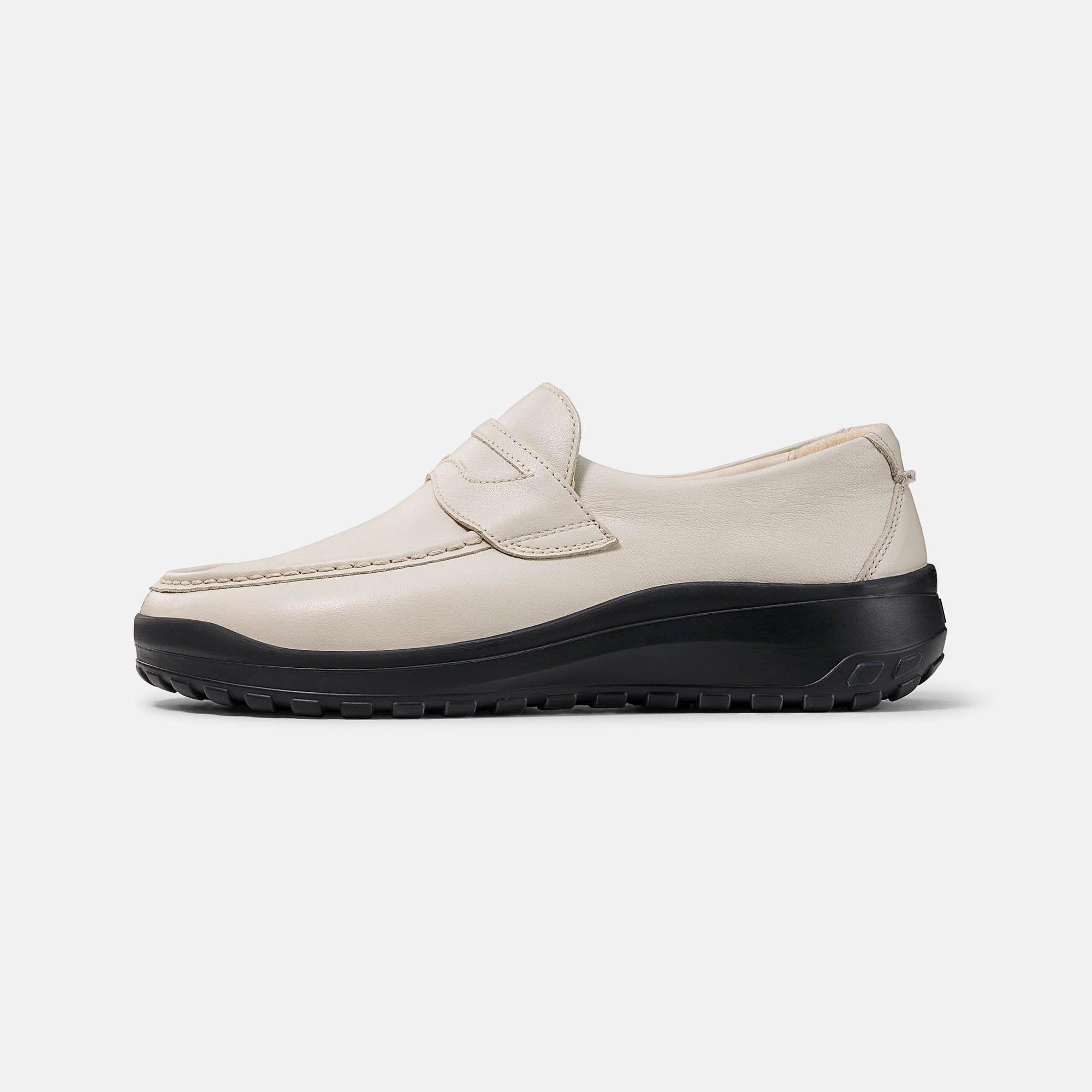 Cremefarbener Slipper mit schwarzer Sohle. Klassisches Design mit Ziernaht und Riemen. Breiter Schnitt.