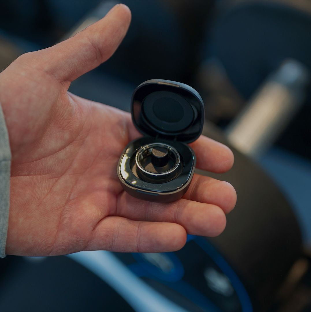 Hand hält eine schwarze, runde Ladestation mit einem Ring. Der Ring ist in der Station.