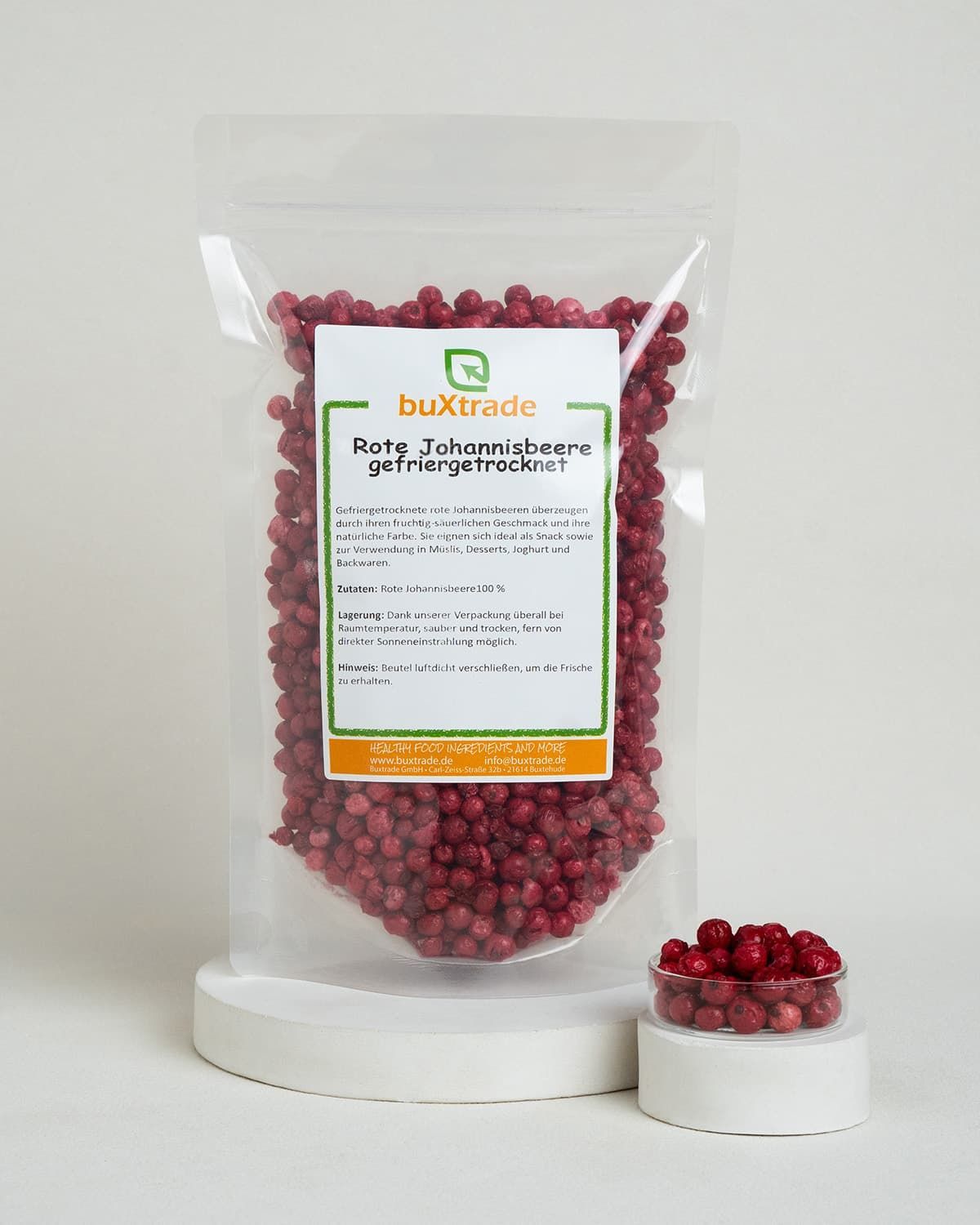 Gefriergetrocknete rote Johannisbeeren in einem Klarsichtbeutel mit Etikett. Kleine Schale mit Beeren daneben.