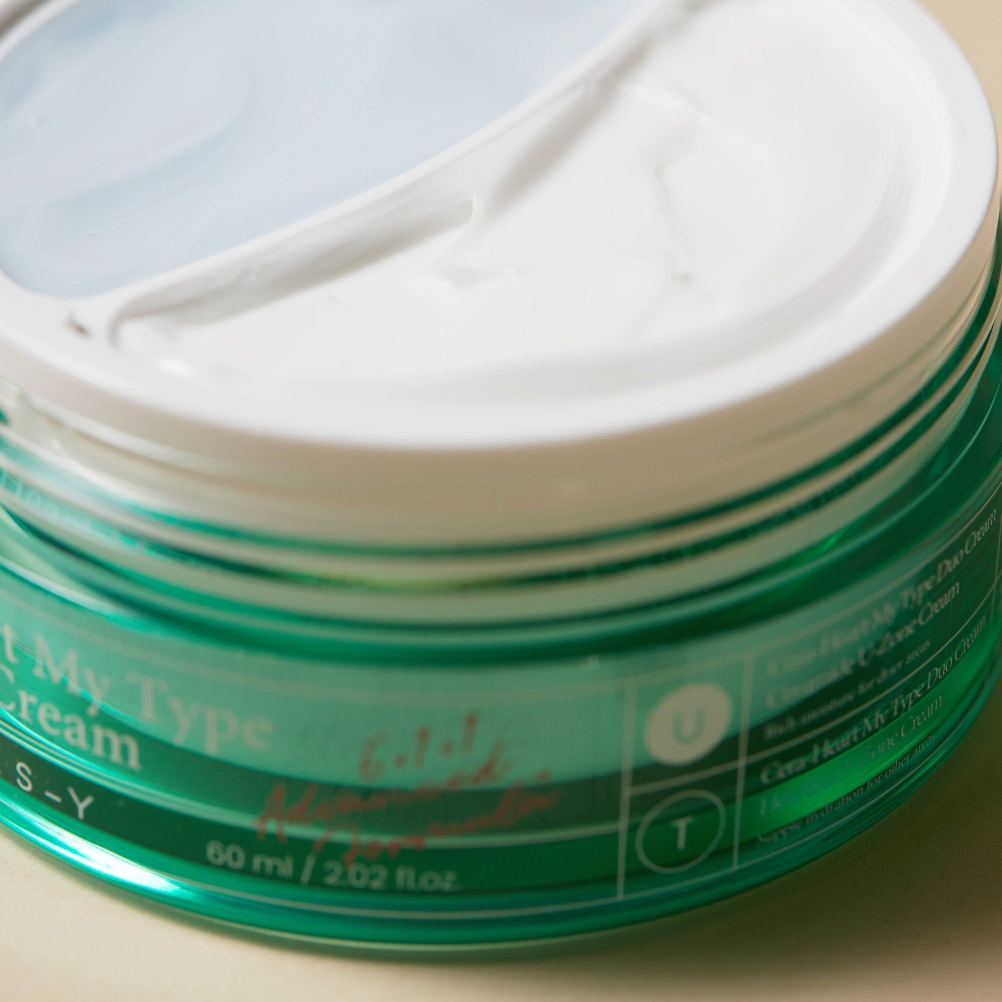 Nahaufnahme einer grünen Creme-Dose mit weißem Deckel. Aufschrift: Cera-Heart My Type Duo Cream. 60 ml.