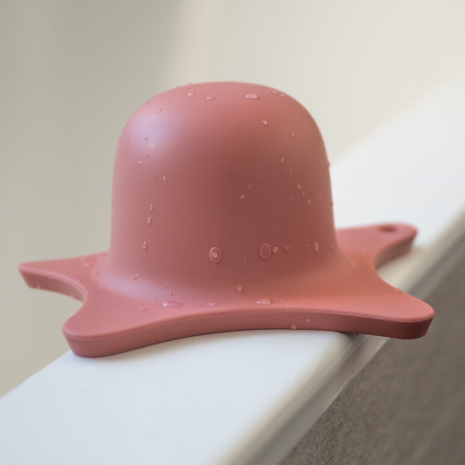 Rosa Duschhilfe mit Wasser. Sternförmige Basis und Kuppel. Auf einer weißen Oberfläche platziert.