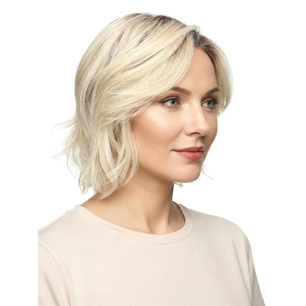 Blond gewellte Perücke. Dreiviertelansicht einer Frau. Dunkler Ansatz, hellere Wellen. Schulterlange Frisur.