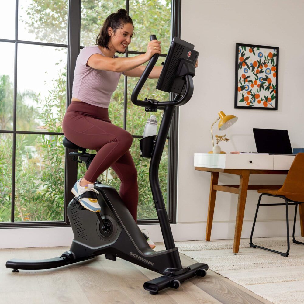 Frau trainiert auf einem Hometrainer. Schwinn Fitness 590U. Wasserflasche am Lenker.