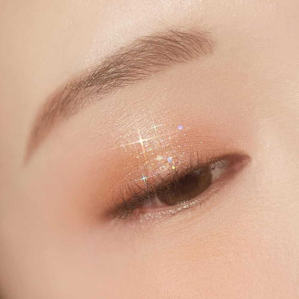 Ein Auge mit schimmerndem Lidschatten und Glitzerpartikeln.