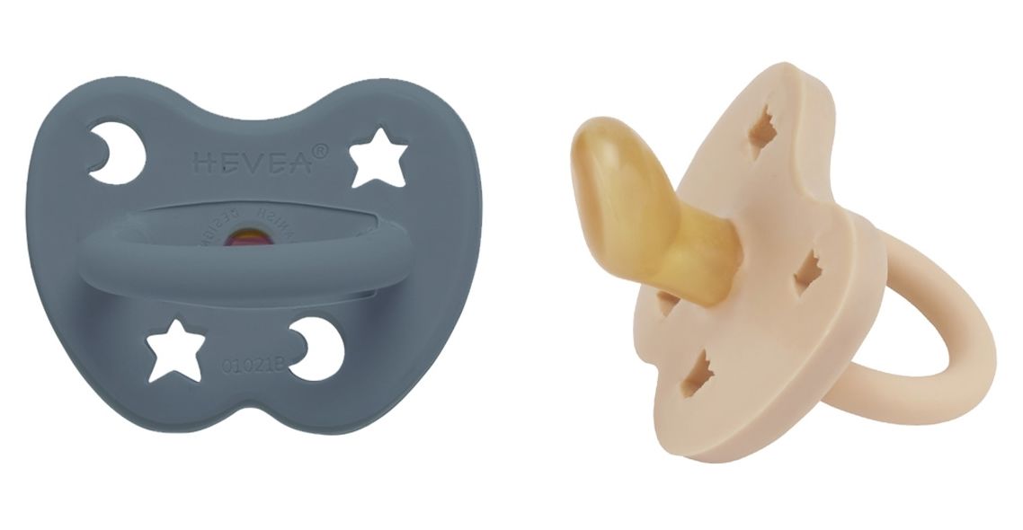 Zwei Schnuller, einer blau, einer beige. Stern- und Mond-Ausschnitte. HEVEA-Logo. Ansicht von oben.