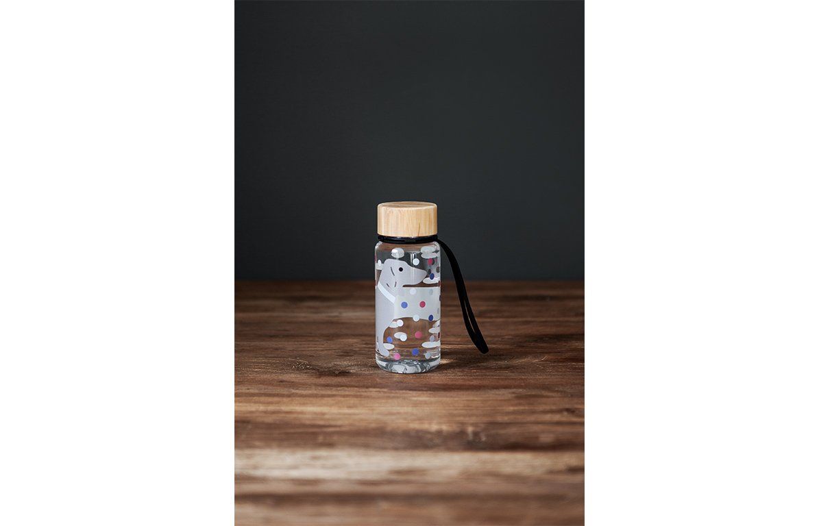 Trinkflasche mit Dackel-Motiv, Tritan, Bambusdeckel, schwarze Schlaufe, auf Holzoberfläche.
