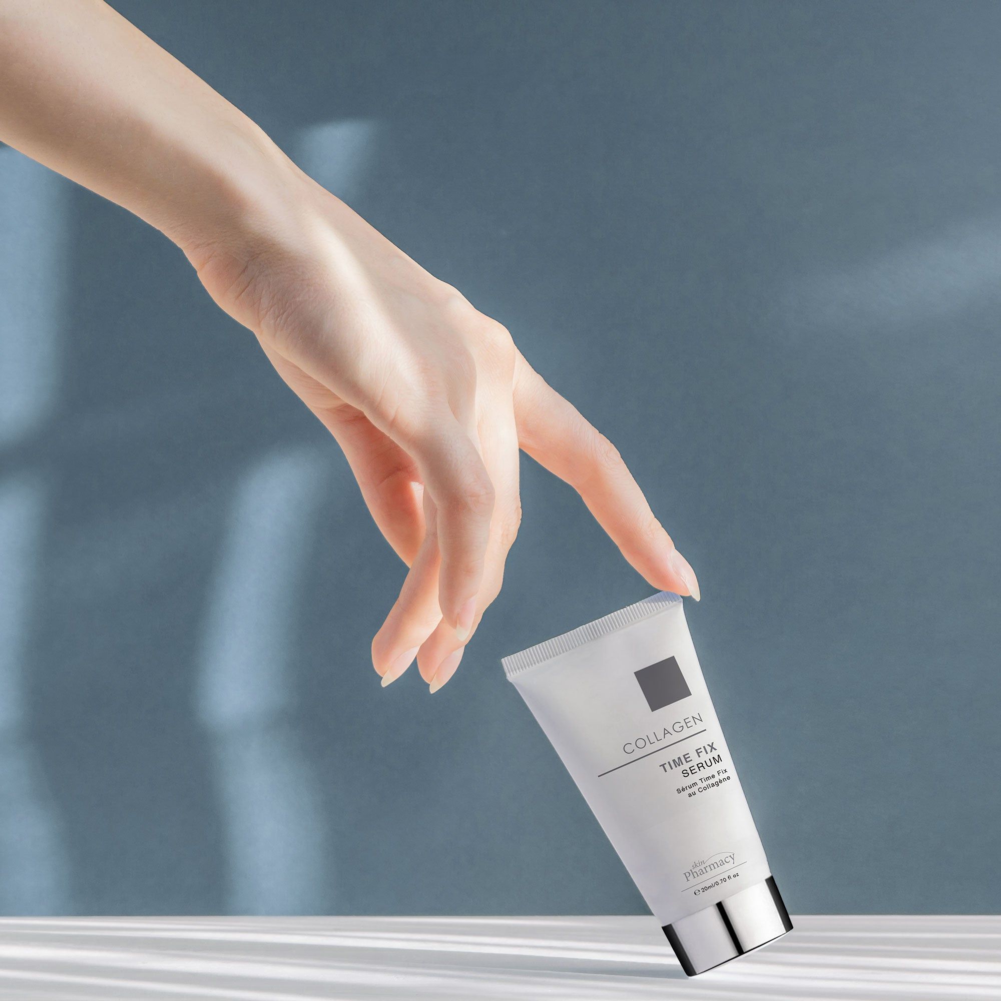 Eine Hand berührt eine weiße Tube. Aufschrift: Collagen Time Fix Serum. Marke: skinPharmacy. Silberne Kappe.