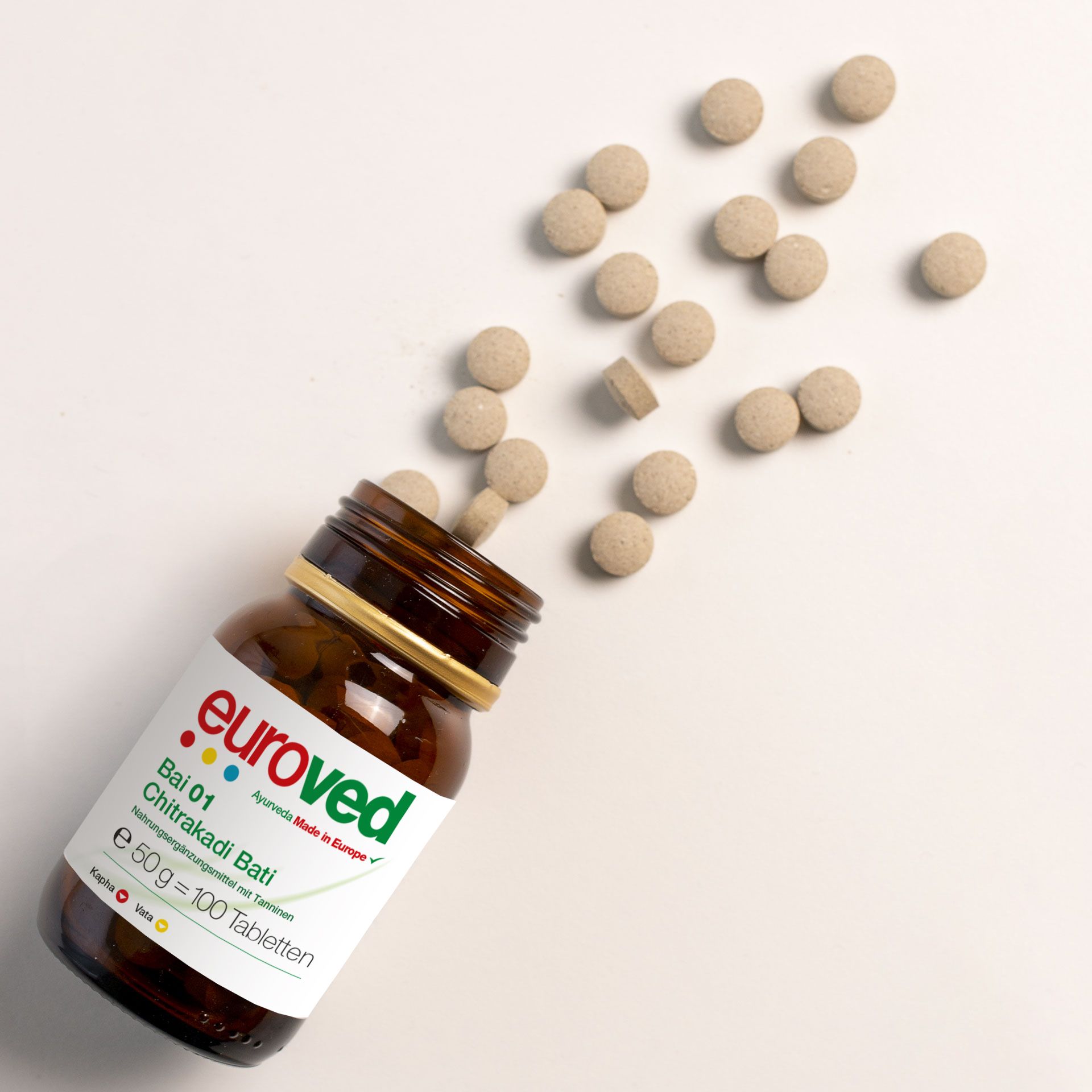 Braune Glasflasche mit Tabletten. Aufschrift euroved, Bai 01 Chitrakadi Bati. Tabletten fallen aus der Flasche.