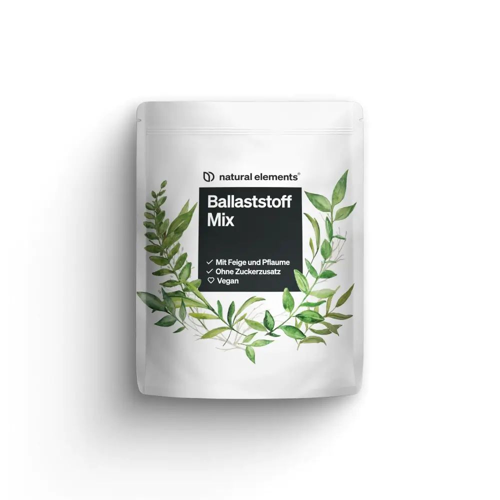 Weiße Beutel mit Aufschrift "natural elements Ballaststoff Mix". Grünpflanzen-Dekoration. Text: Mit Feige und Pflaume, Ohne Zuckerzusatz, Vegan.