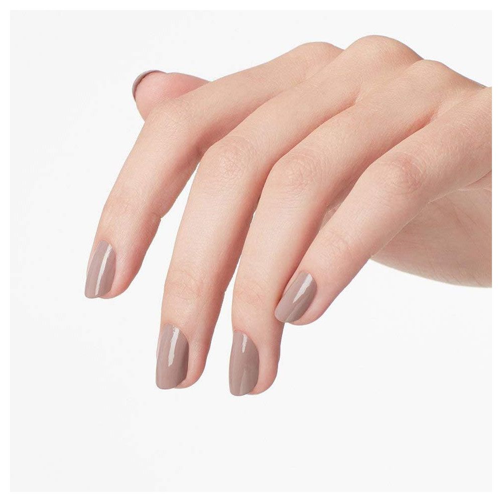 Hand mit lackierten Nägeln in Taupe. Fingernägel sind mit Nagellack bedeckt.