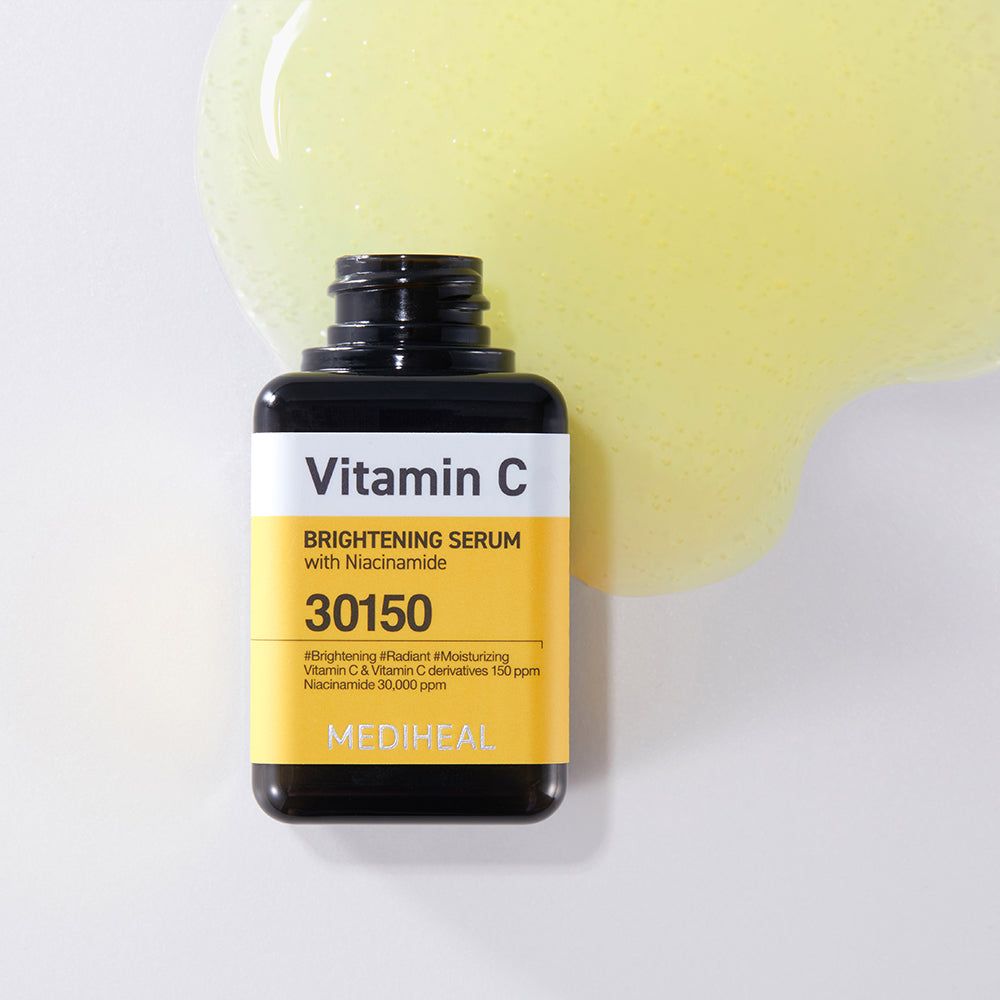 Flasche Mediheal Vitamin C Serum auf weißem Hintergrund mit einem großen Tropfen gelbem Serum daneben.