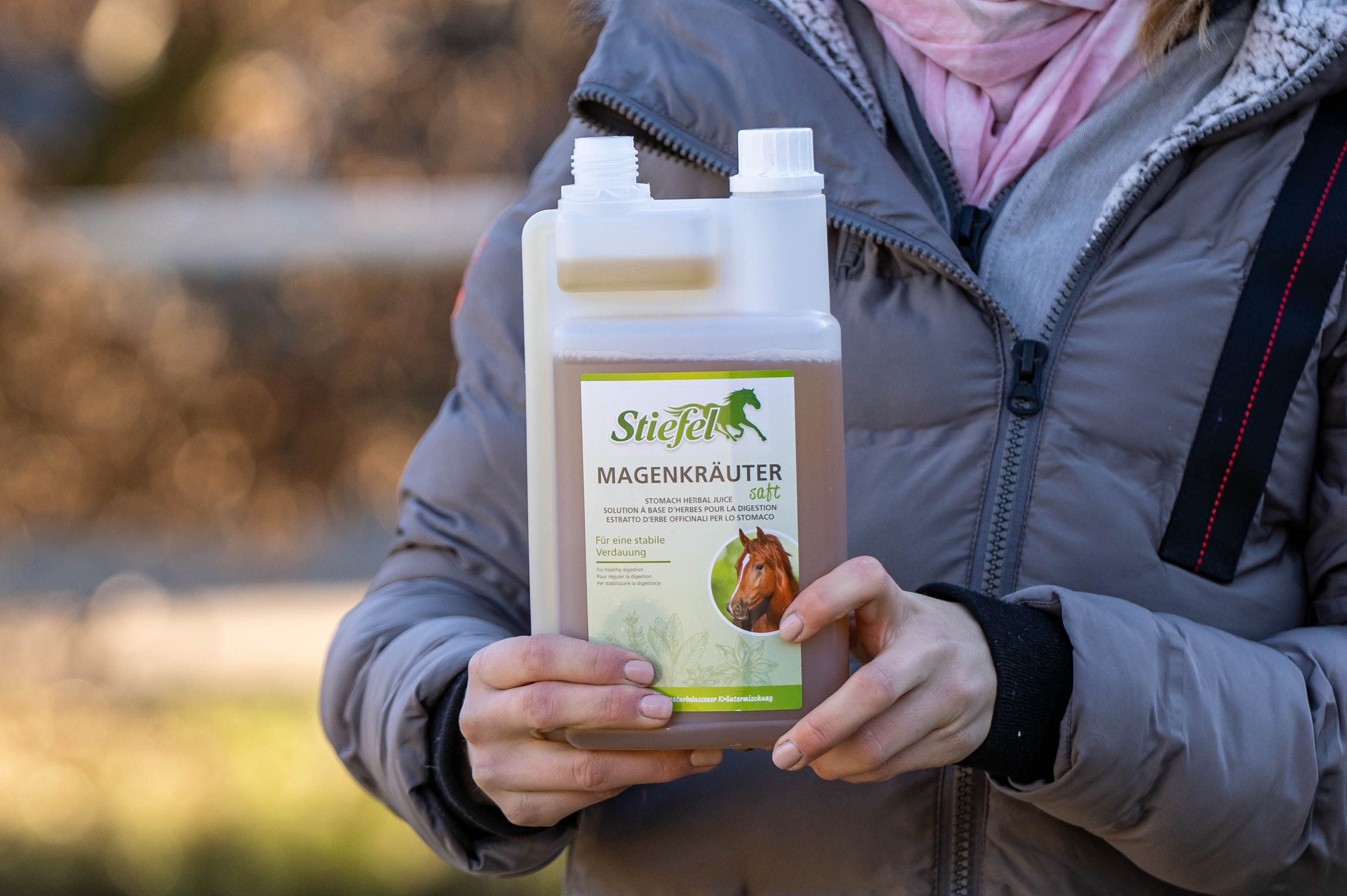 Person hält eine Flasche Kräutersaft. Label mit Produktnamen und Logo. Flasche mit zwei Kammern.