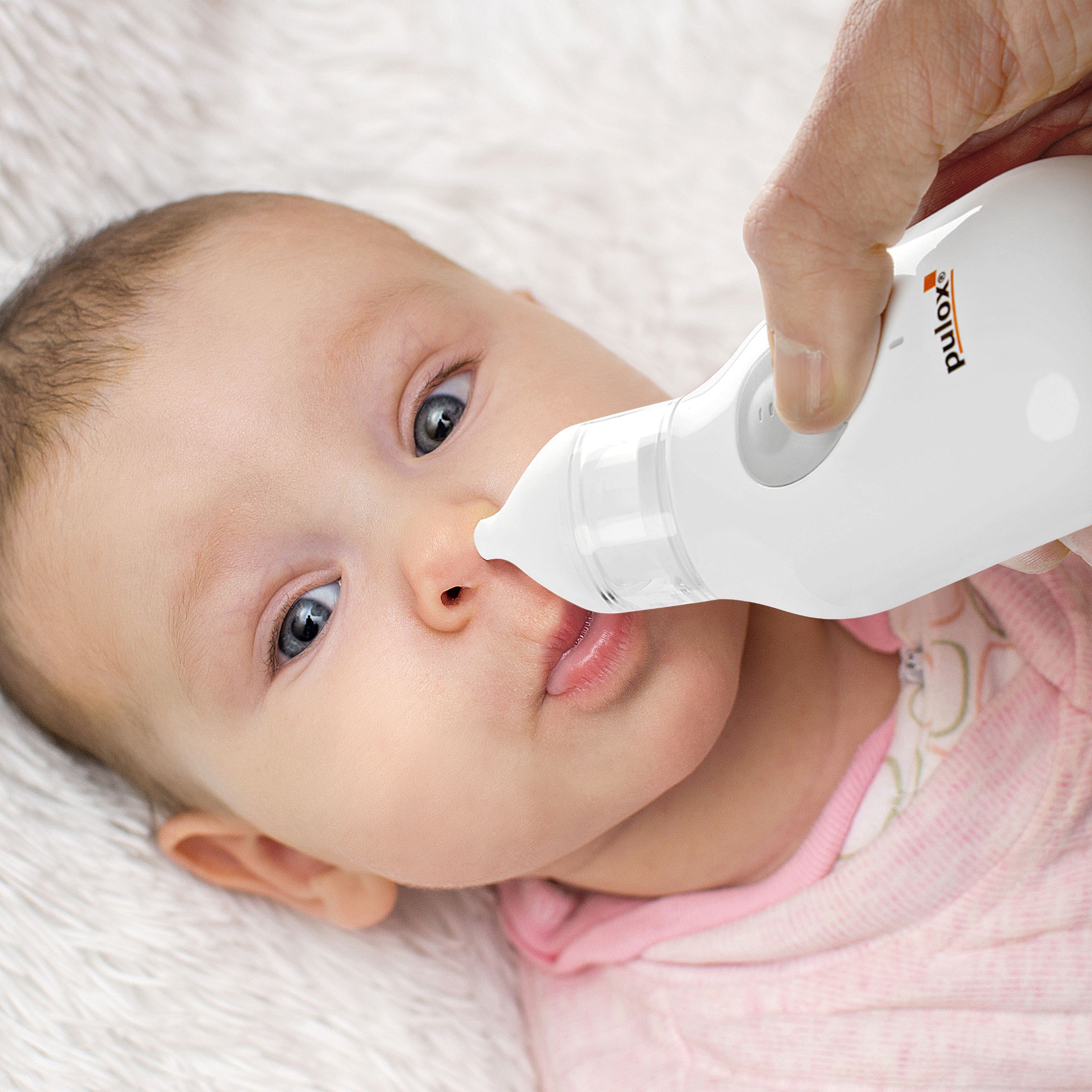 Elektrischer Nasensauger wird von einer Hand an der Nase eines Babys angewendet.