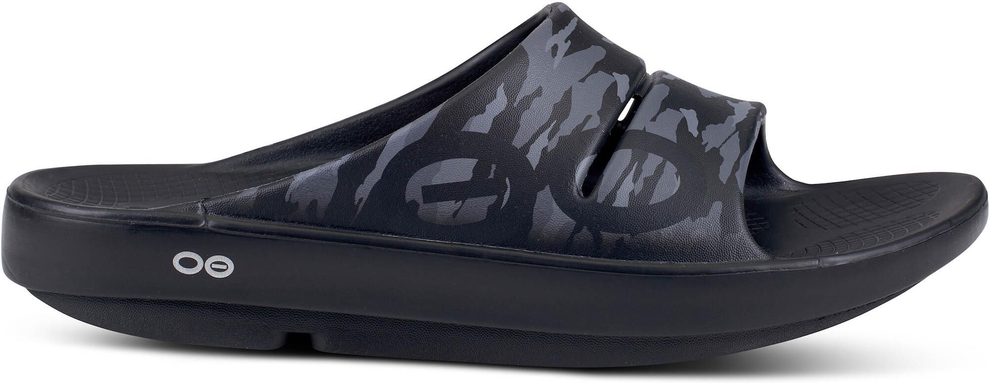 Schwarze Sandale mit Camouflage-Muster. Seitliche Ansicht. OOFOS-Logo sichtbar. Dicke Sohle.