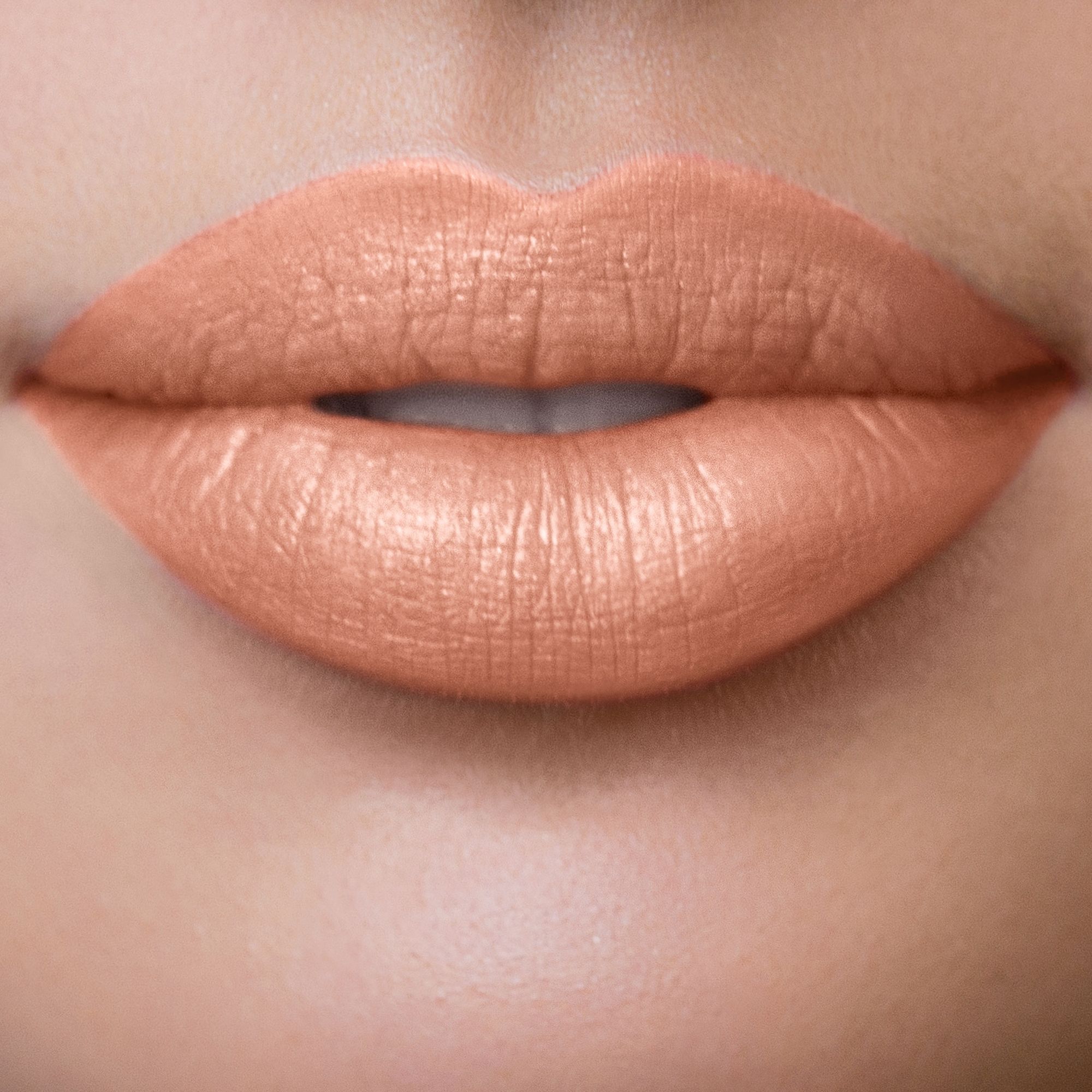Nahaufnahme von Lippen, die mit einem Nude-Farbton geschminkt sind.