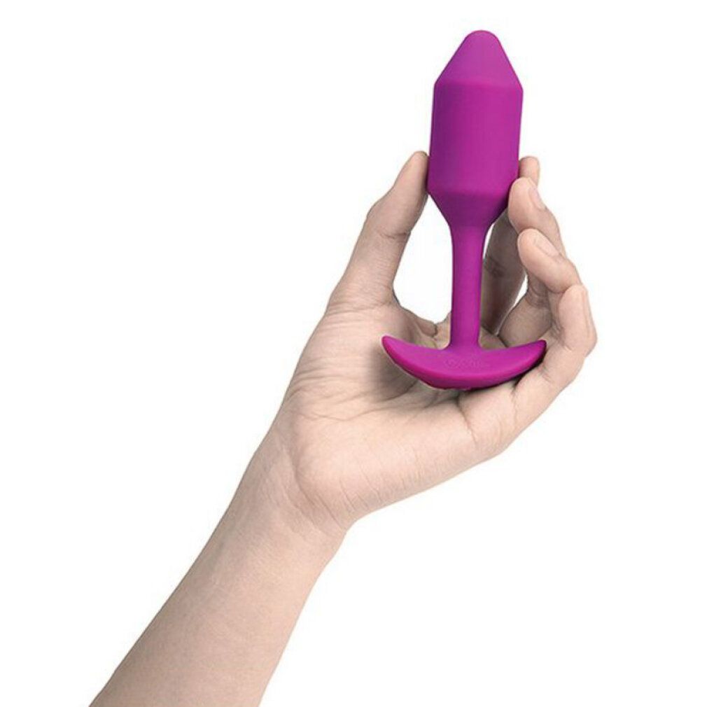 Lila Plug in Hand gehalten. Kegelförmige Spitze, T-förmige Basis.