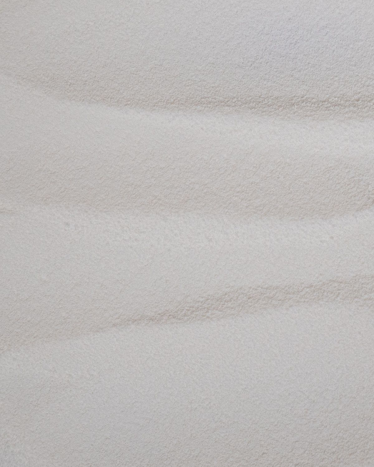 Nahaufnahme von weißem Pulver mit wellenförmiger Textur. Helle Beleuchtung.