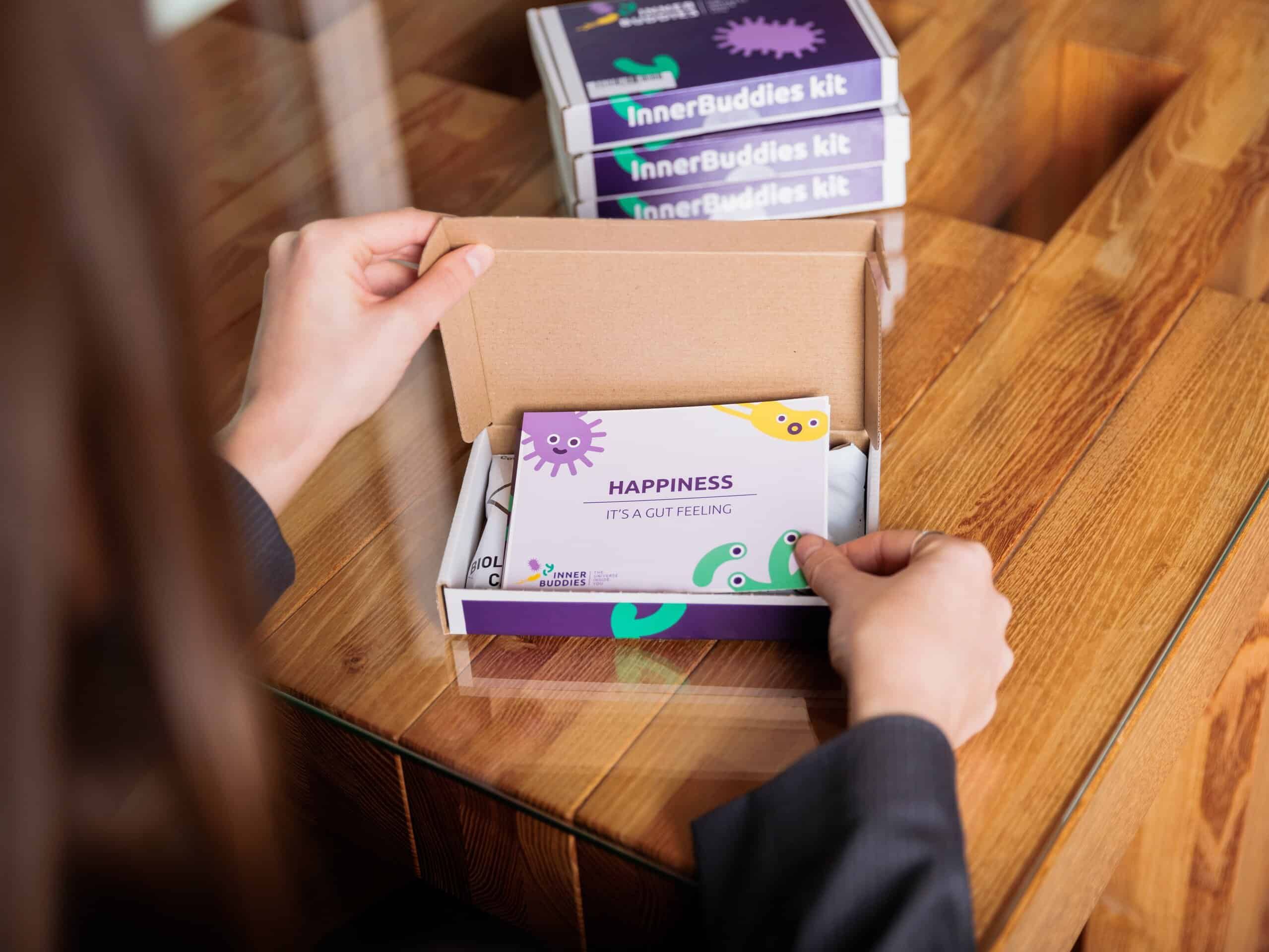 Person öffnet eine Inner Buddies Testkit-Verpackung und enthüllt den Inhalt.