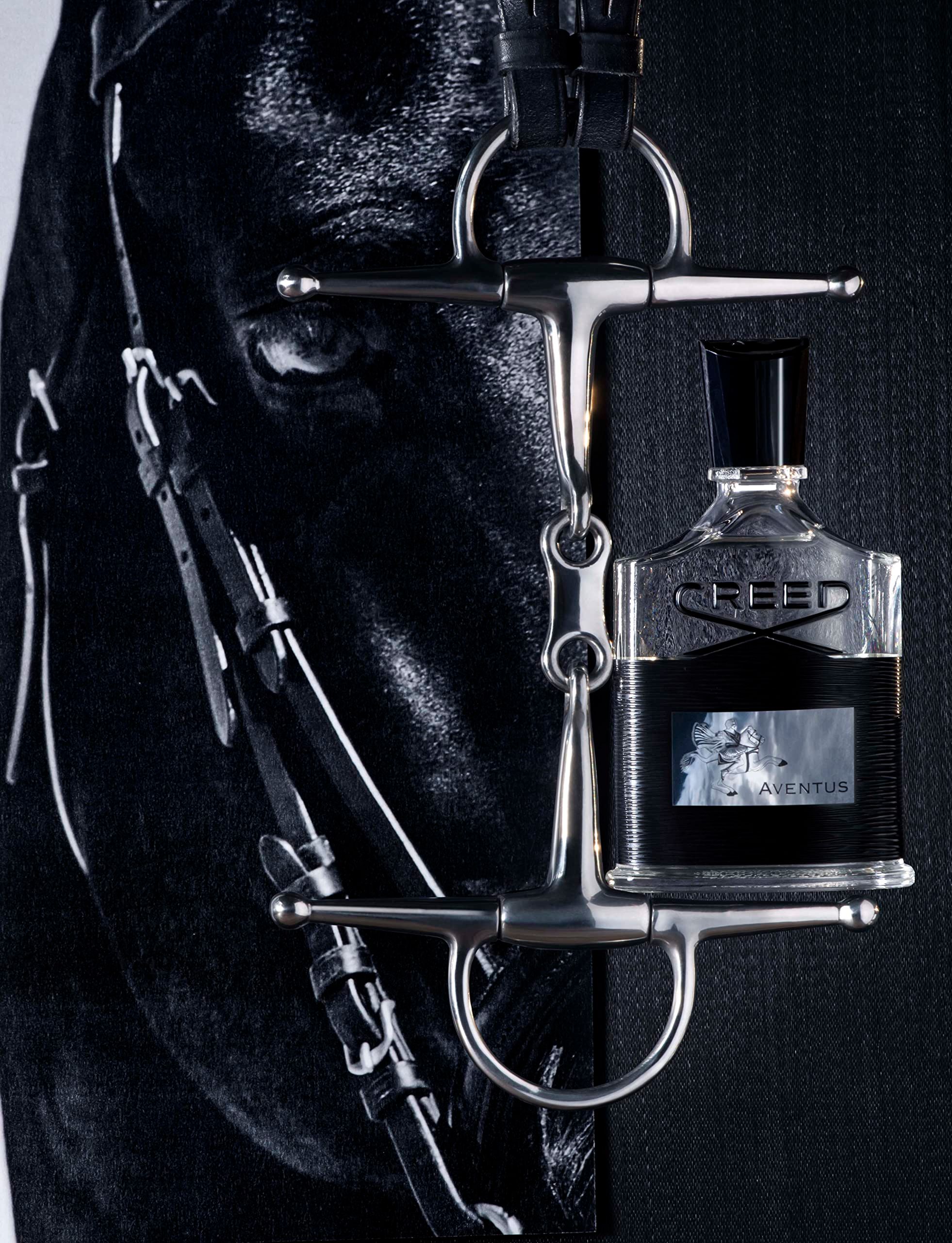Parfümflakon mit schwarzem Deckel. Aufschrift „CREED“ und „AVENTUS“. Neben einem Zaumzeug.
