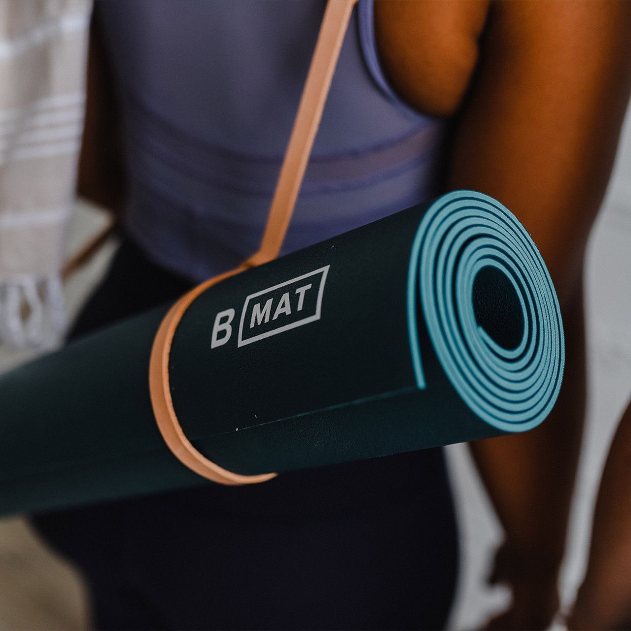 Gerollte Yogamatte, Ocean Green, mit Trageriemen. Logo B MAT sichtbar.