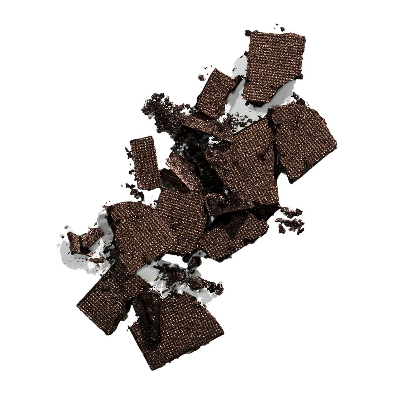 Dunkelbraune, zerbrochene Puderstücke auf weißem Hintergrund. Strukturierte Oberfläche.