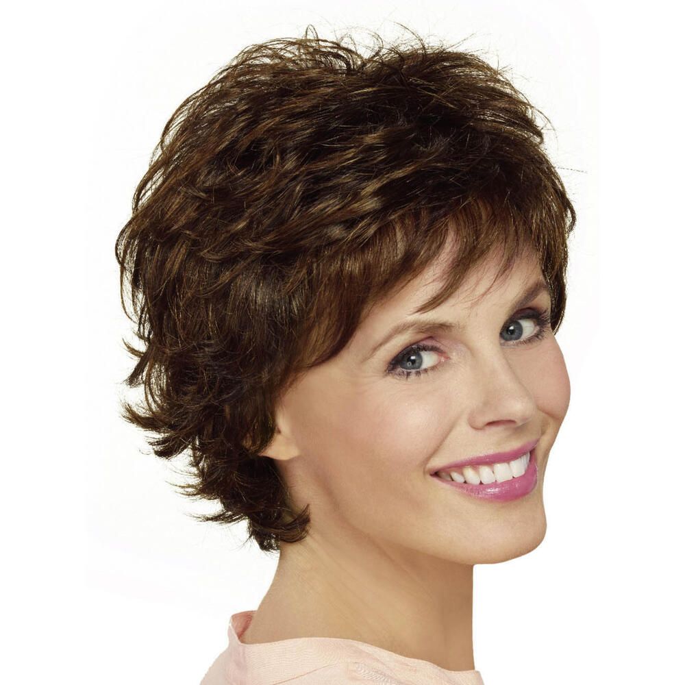 Kurzhaarperücke in Braun mit fransigem Schnitt. Frau mit Perücke lächelt in die Kamera. Helle Haut, rosa Oberteil.