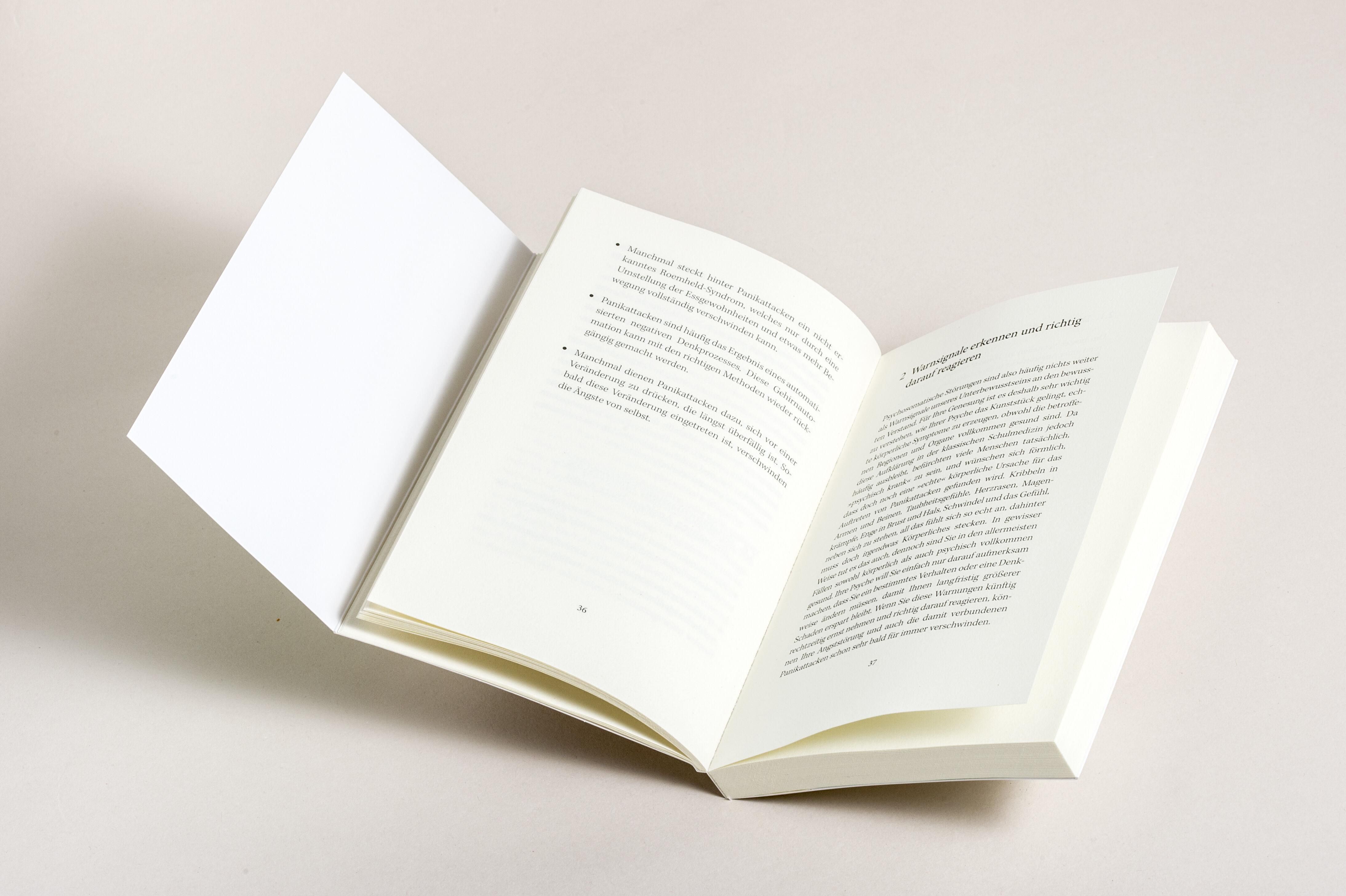 Buch, aufgeschlagen. Linke Seite mit Text. Rechte Seite mit Text. Buch liegt schräg.