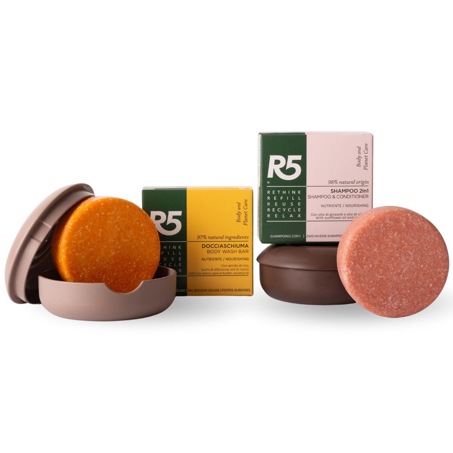 Zwei runde Seifenstücke in Halterungen, zwei Seifenstücke in Schachteln. Text: R5, Shampoo 2-in-1, Docciaschiuma.