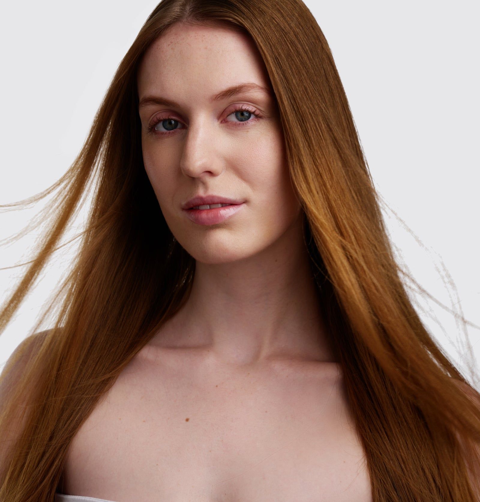 Porträt einer Person mit langen, roten Haaren. Die Haare sind glatt und fallen um das Gesicht.