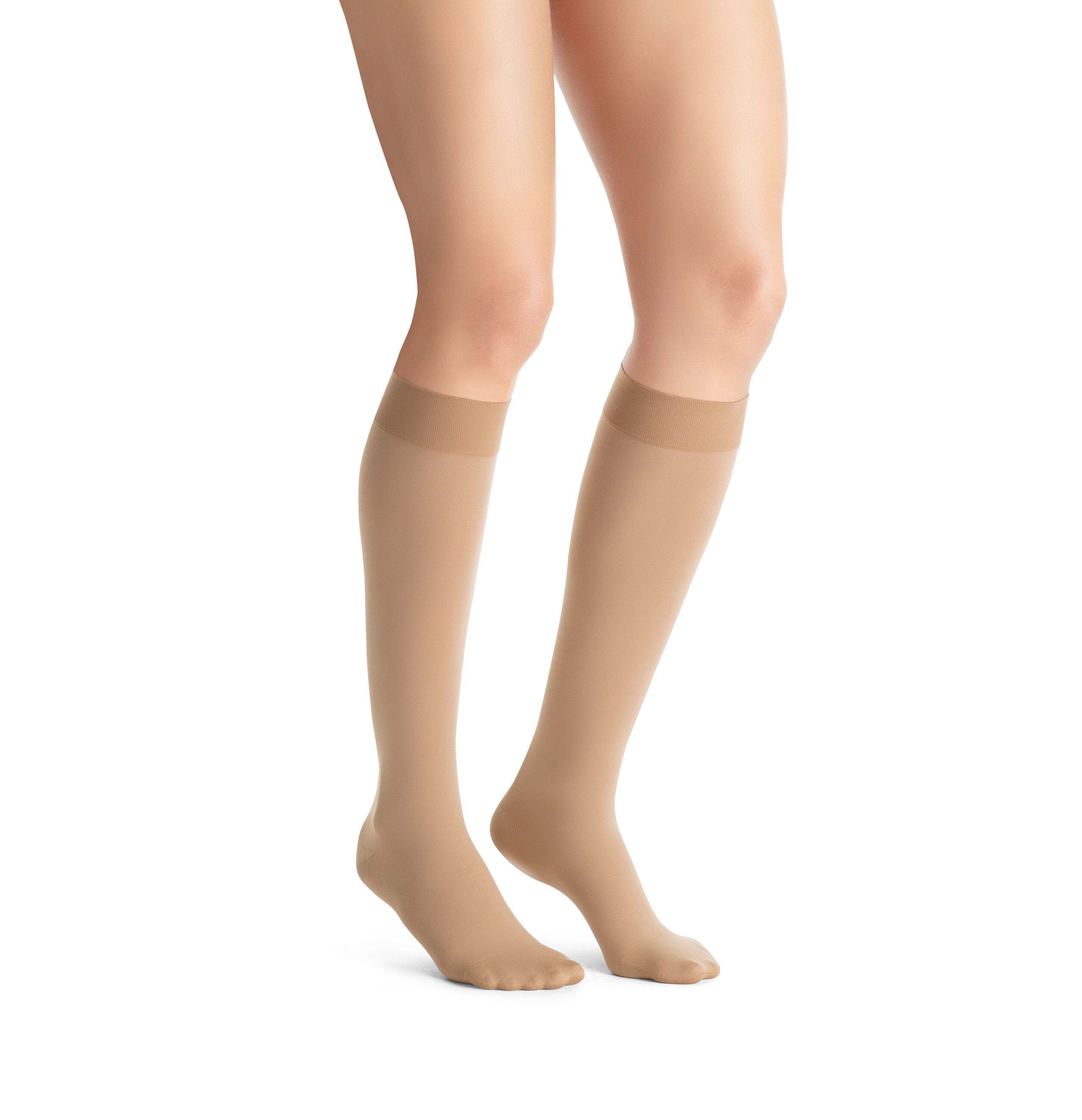 Helle Kompressions-Kniestrümpfe an Beinen. Beige Strümpfe mit verstärktem Zehen- und Fersenbereich. Kniestrümpfe reichen bis unter das Knie.