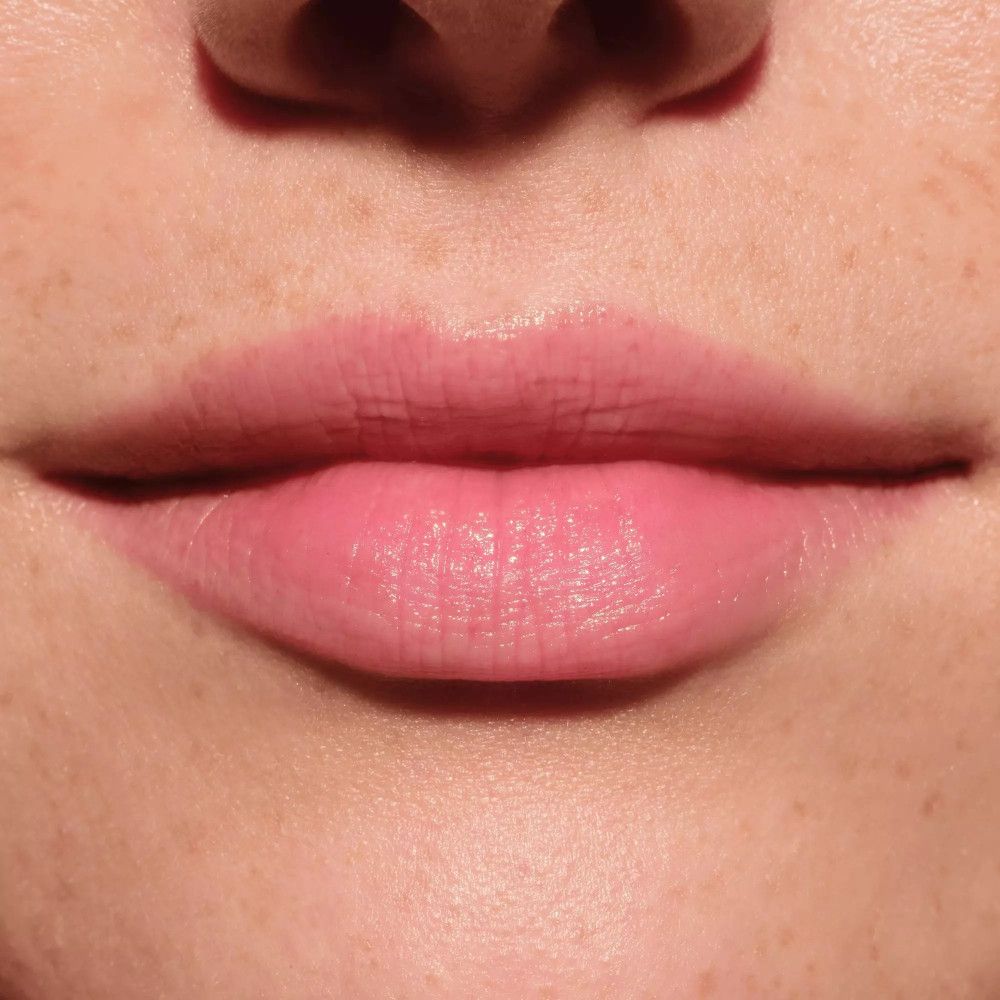 Nahaufnahme von Lippen. Sie sind mit Lippenbalsam befeuchtet und leicht rosa.