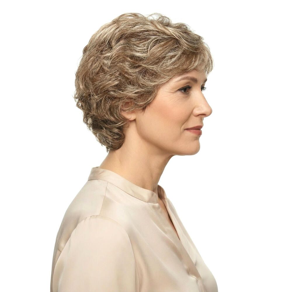 Perücke MONACO. Blond-meliertes Kunsthaar. Seitenansicht einer Frau. Sie trägt eine beige Bluse. Der Hintergrund ist weiß.