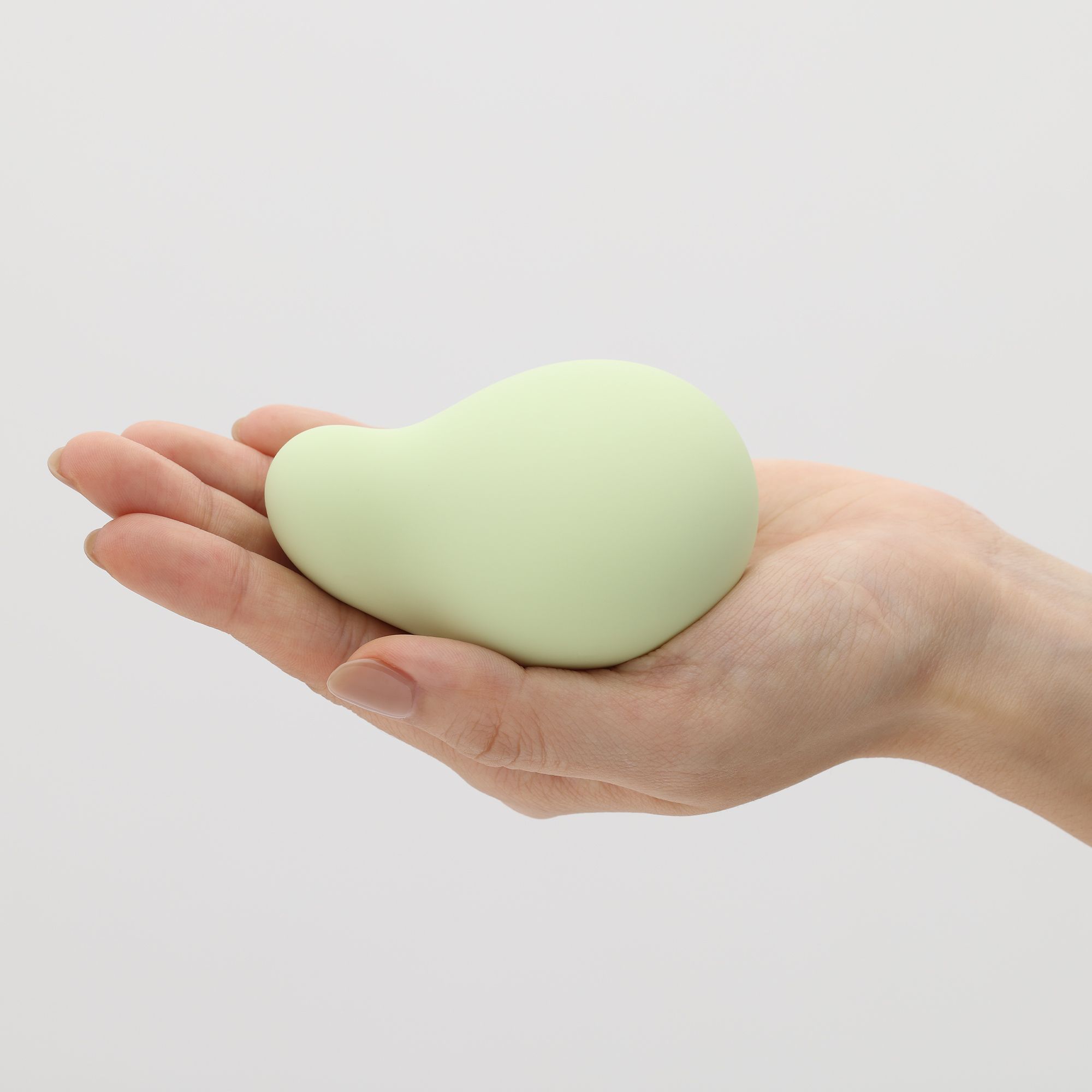 Hellgrüner, birnenförmiger Vibrator in einer Hand gehalten. Glatte Oberfläche.