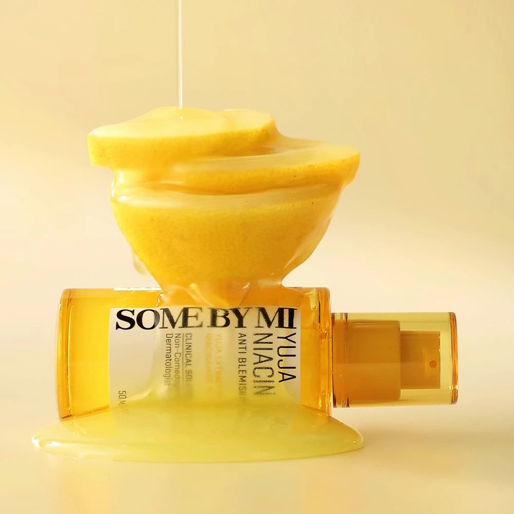 Gelbes Serumfläschchen mit Sprühkopf, daneben Zitronenscheiben. Aufschrift: SOME BY MI Yuja Niacin Anti-Blemish.