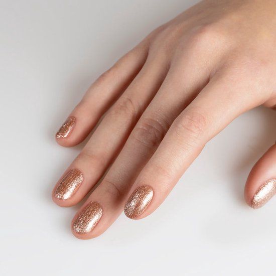 Hand mit lackierten Nägeln in Rosa-Gold. Hintergrund weiß.