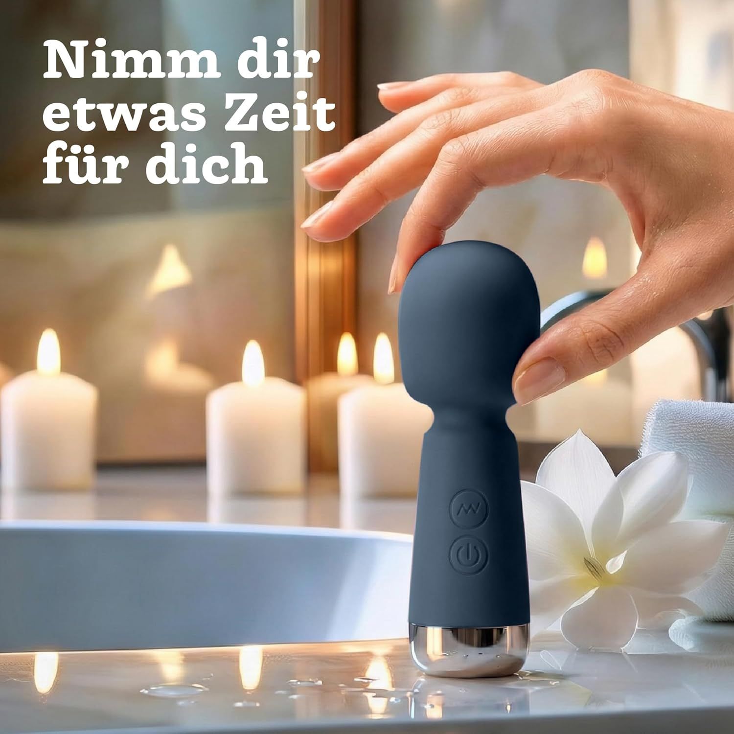 Hand hält blauen Mini Vibrator vor Kerzenlicht und einer Blüte. Stimmungsvolle Beleuchtung.