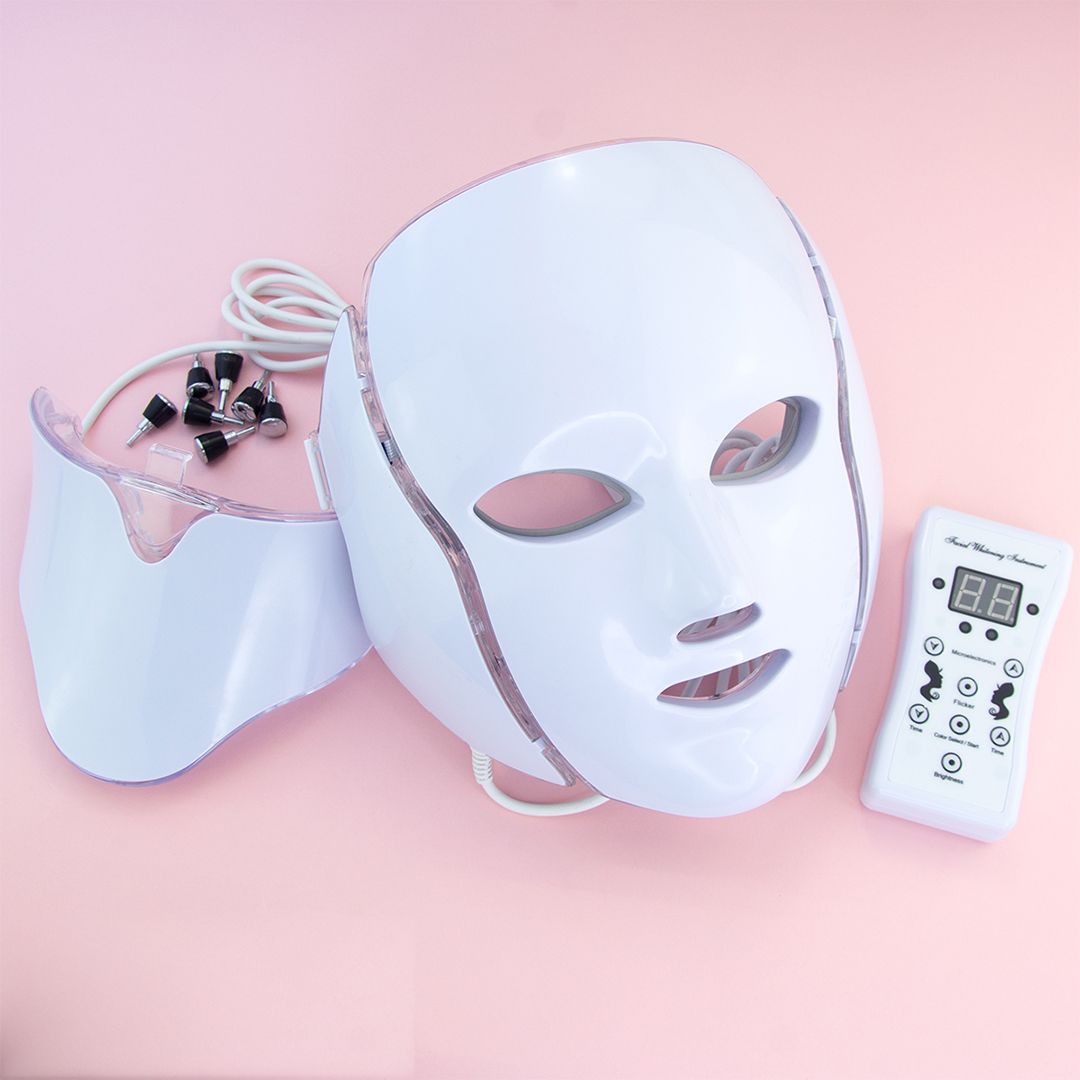Weiße LED-Gesichtsmaske mit Halsansatz, Fernbedienung und Zubehör. Die Maske hat Öffnungen für Augen, Nase und Mund.
