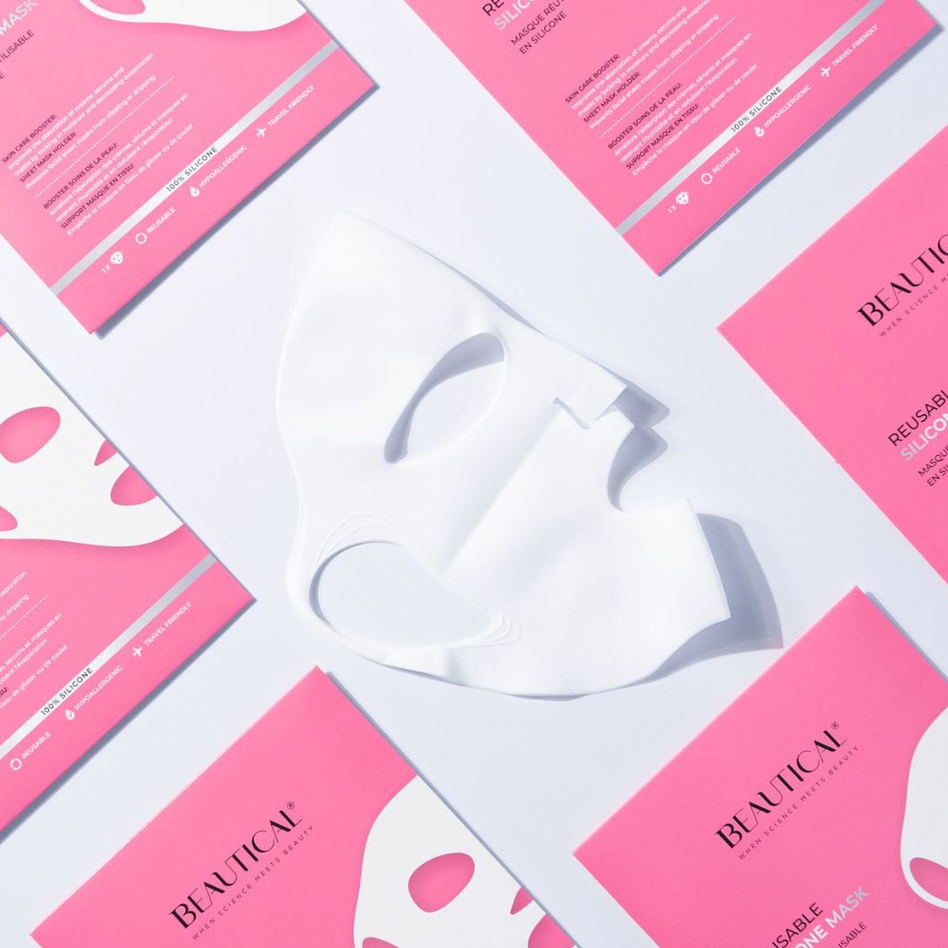 Masque en silicone blanc et emballages roses. Texte: BEAUTICAL, REUSABLE SILICONE MASK. Disposition sur fond blanc.