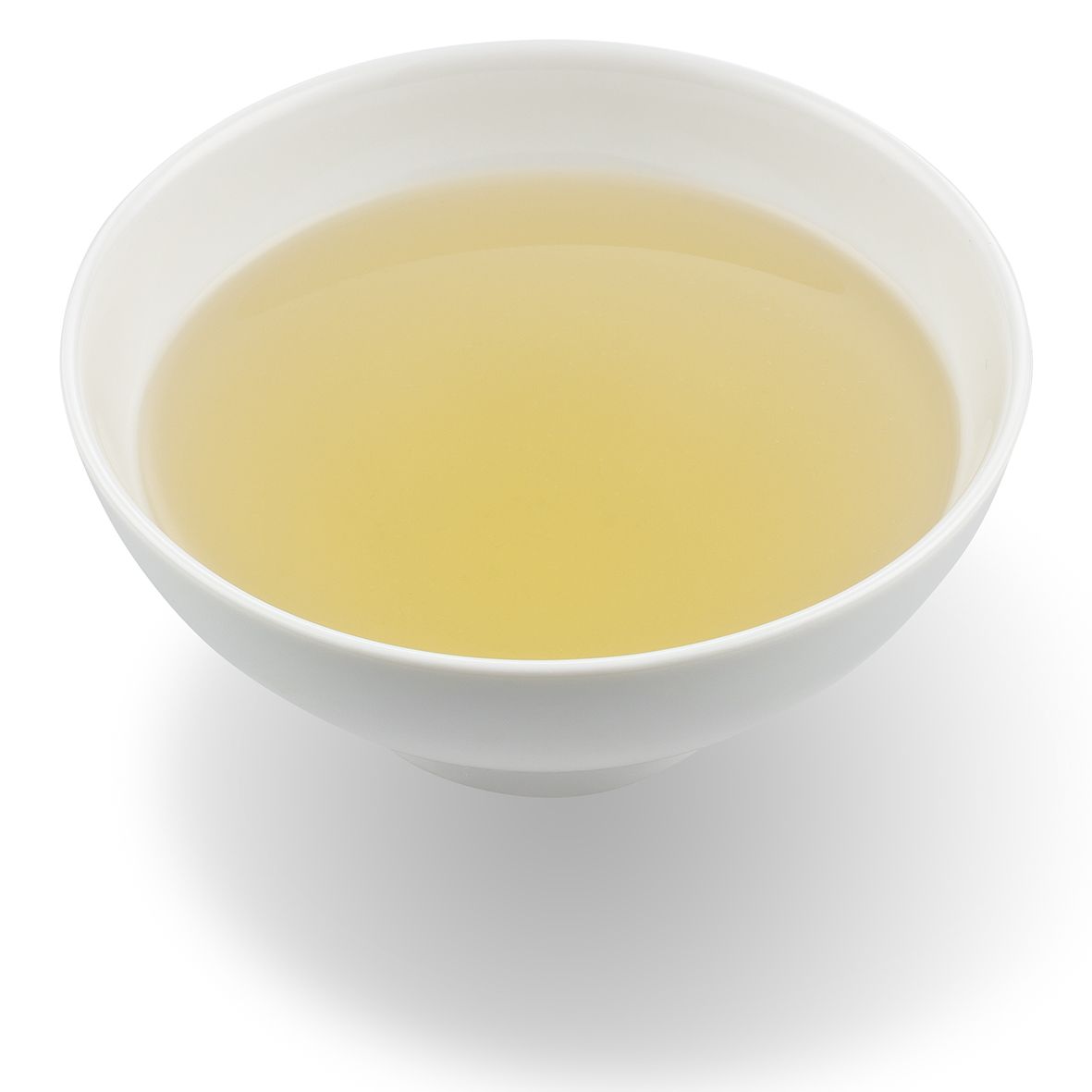 Weiße Schüssel mit gelbem Tee. Flüssigkeit im Inneren. Schatten unter der Schüssel.