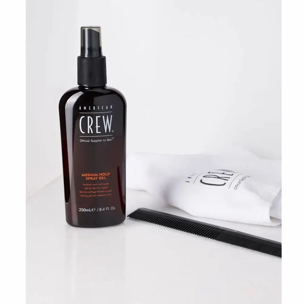 Braune Flasche mit schwarzem Sprühkopf. Beschriftung: American Crew, Medium Hold Spray Gel. Mit Kamm und Beutel.