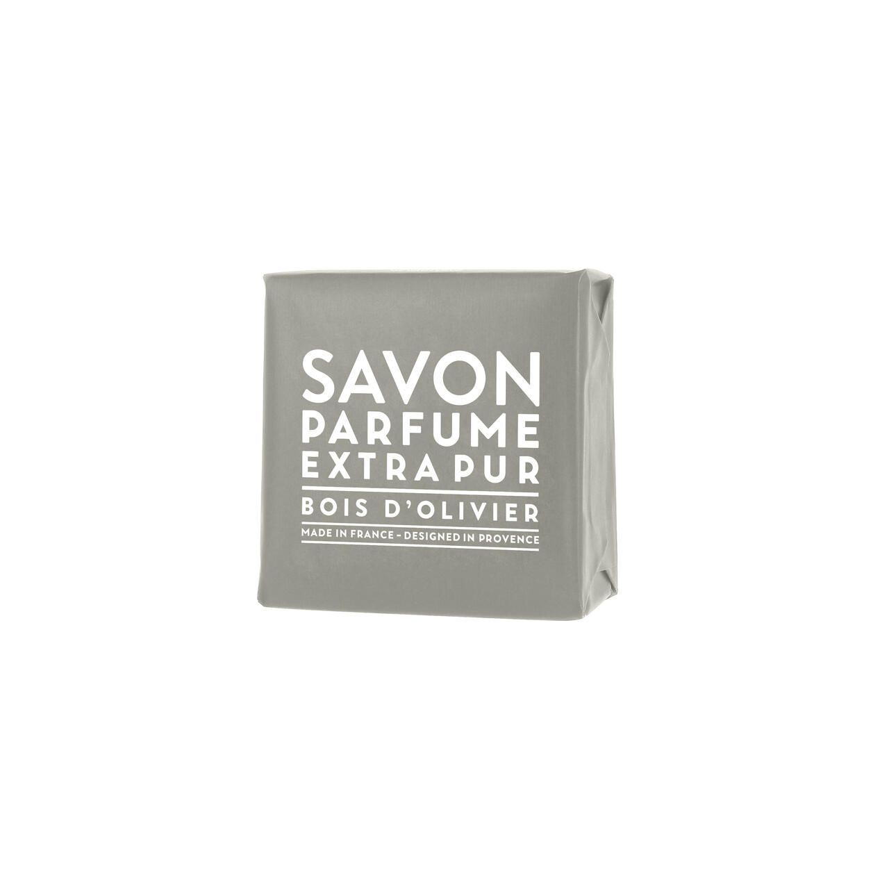 Graues Seifenstück in Papier verpackt. Text: Savon Parfume Extra Pur Bois d'Olivier. Hergestellt in Frankreich, entworfen in der Provence.