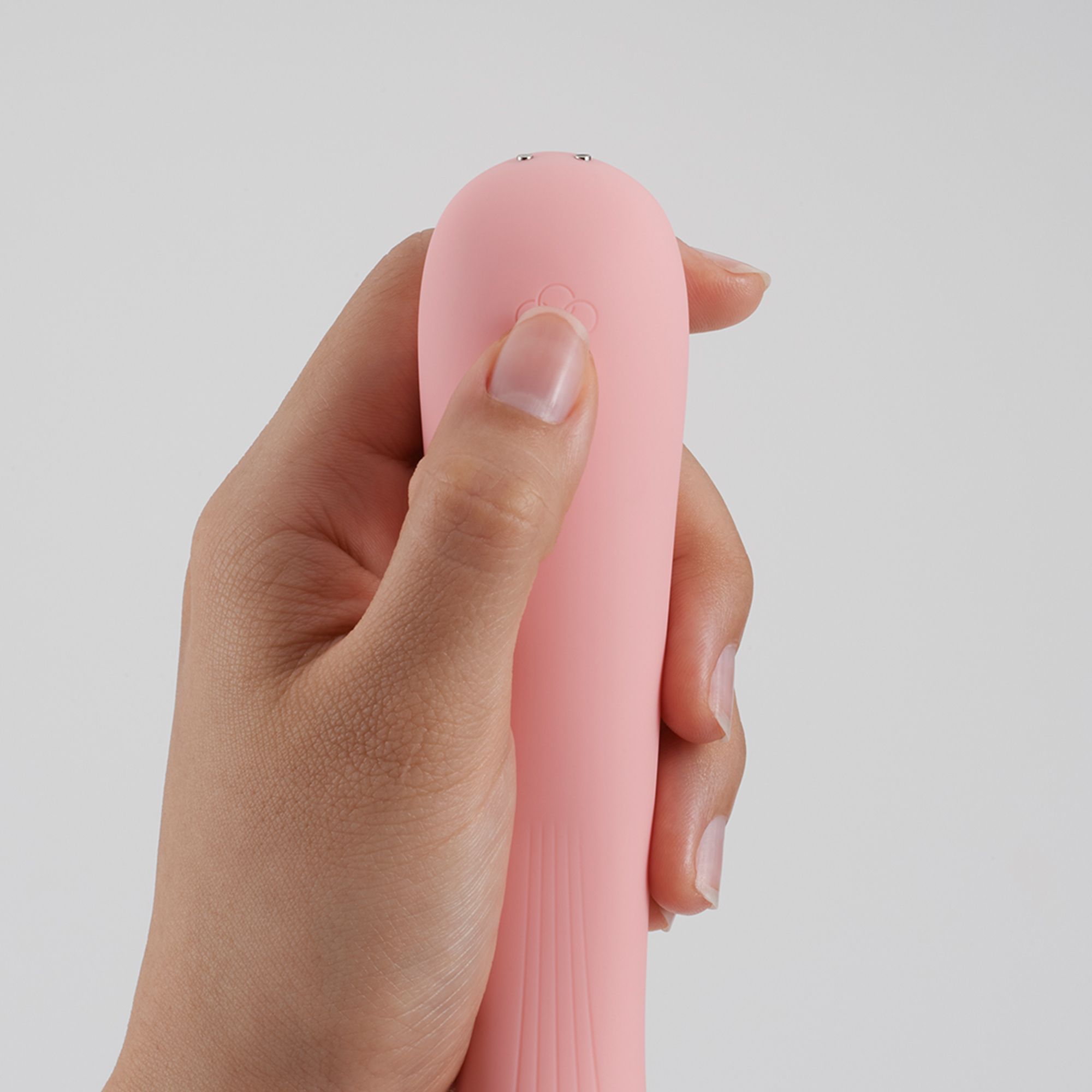 Hand hält rosa Vibrator. Sichtbarer Knopf. Produktname nicht sichtbar.