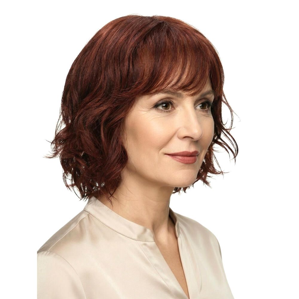 Rote Perücke mit gewelltem Haar und Pony. Seitenansicht einer Frau mit hellem Oberteil.