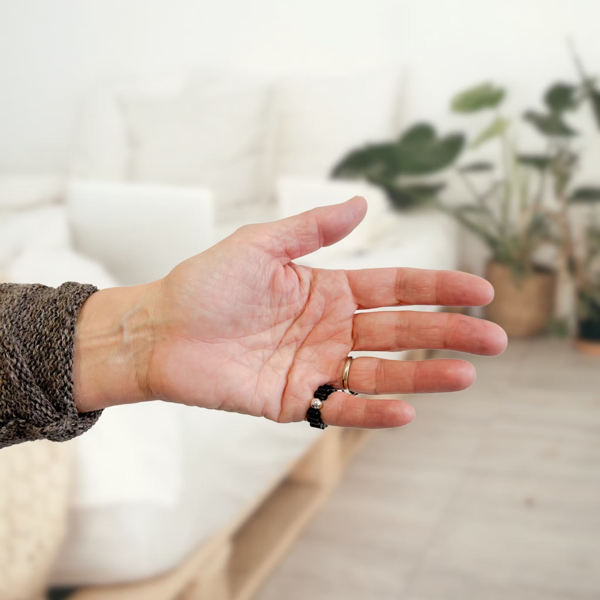 Hand mit schwarzem Ring mit silberner Kugel. Wellness-Produkt.
