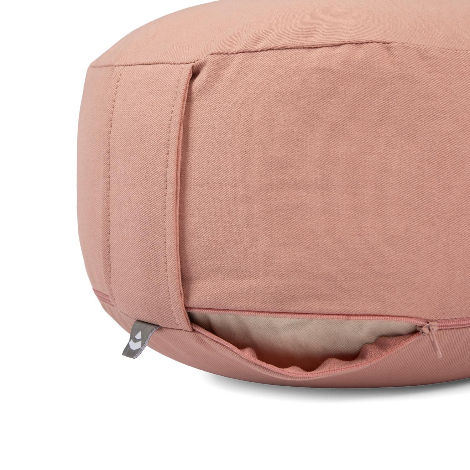 Nahaufnahme eines roséfarbenen Meditationskissens mit geöffnetem Reißverschluss und sichtbarer Füllung.