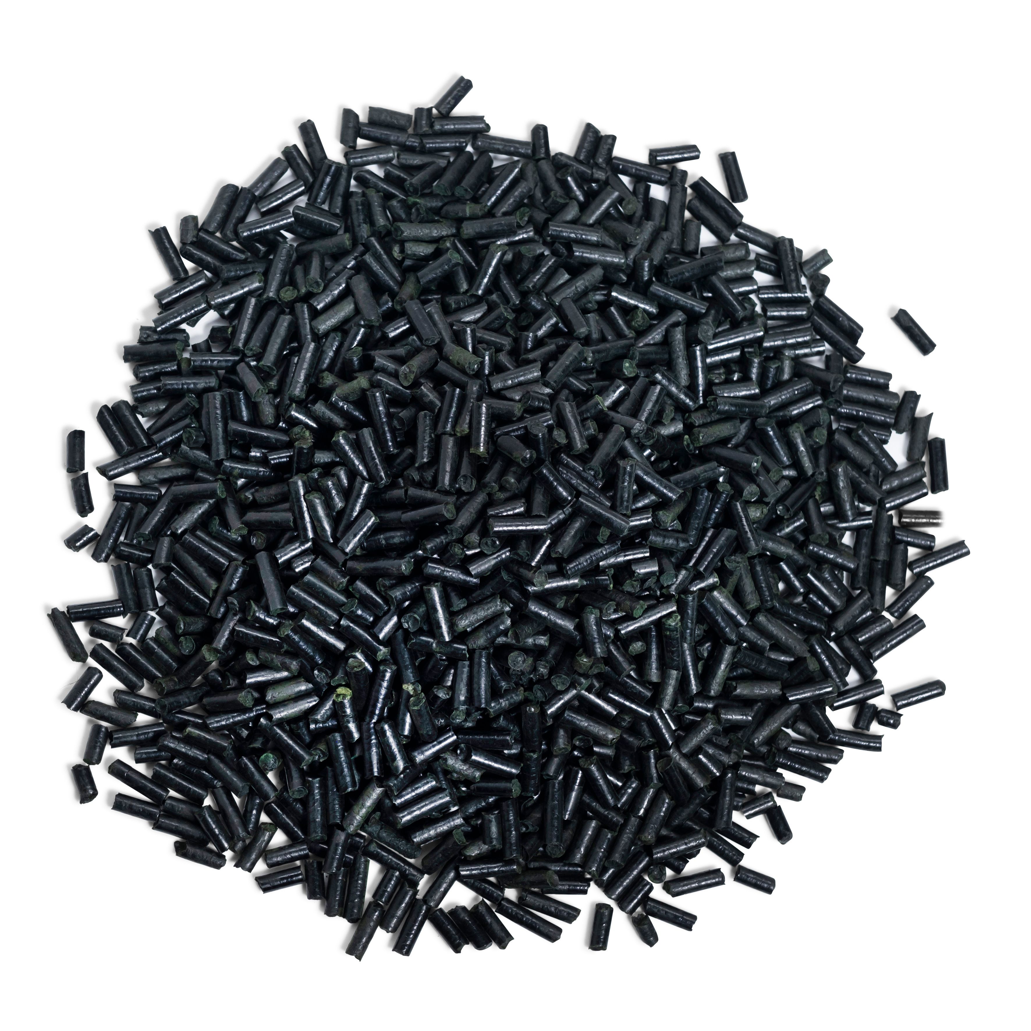 Haufen schwarzer Spirulina Pellets. Zylindrische Form, dunkel gefärbt. Auf weißem Hintergrund.