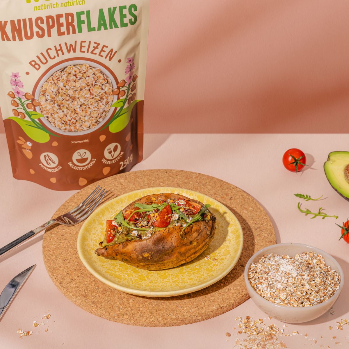 Verpackung NutriPur Knusperflakes Buchweizen. Beutel mit Flocken, 250g. Auf Teller: Ofenkartoffel mit Belag. Schale mit Flocken.