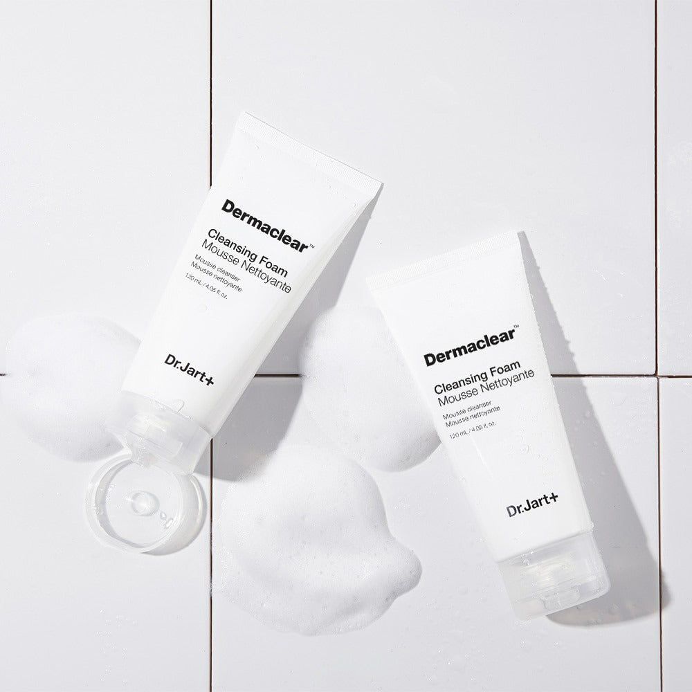 Zwei weiße Tuben mit Produktnamen und Text, umgeben von Schaum. Auf weißem Untergrund.